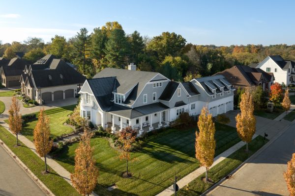 Aerial view of an estate-like home in a Louisville neighborhood. Expansive yard with fall time trees and beautiful blue sky. A prime piece of Louisville Real Estate